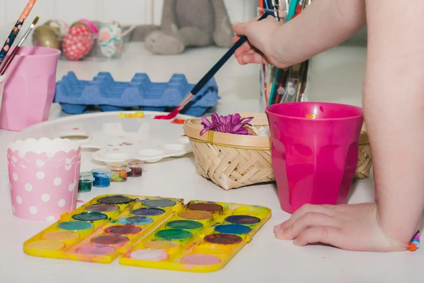 Bildausschnitt eines Kindes, das Farbe für ein Ei nimmt.