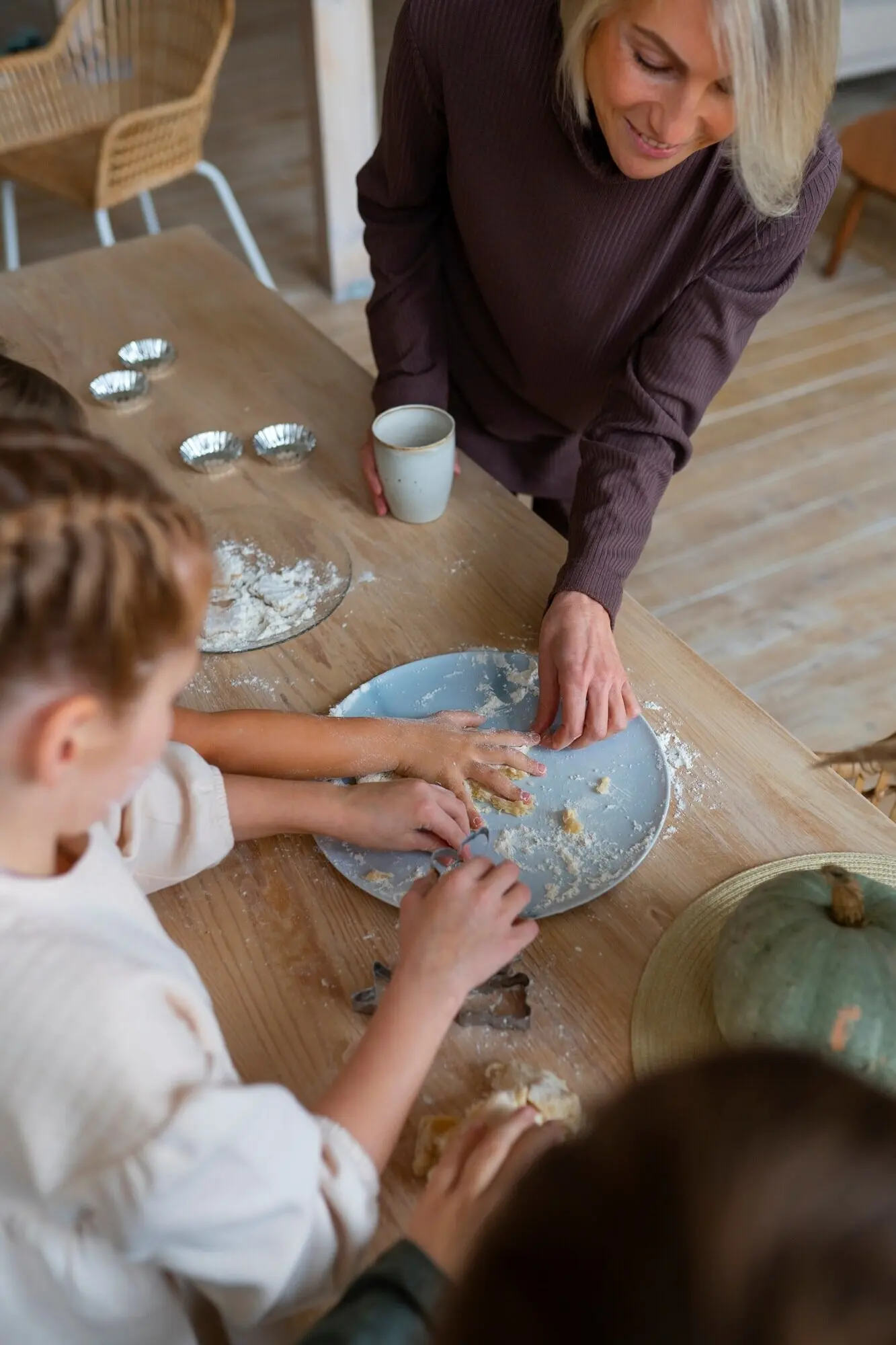 Eine Frau hilft Kindern beim Kochen, Aufnahme von oben.